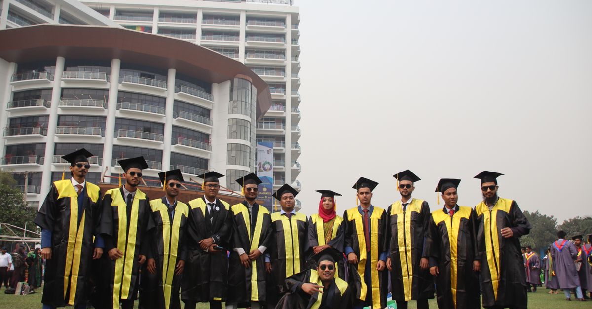 Graduating students celebrating with friends in front of university building.